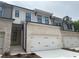 A new construction townhome features light brick, a two-car garage, black gutters, and a yellow front door at 1366 Lucan Ln # Wc225, Lawrenceville, GA 30043