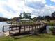 Wooden bridge stretches over lake towards a gazebo and playground beyond the still water at 1366 Lucan Ln # Wc225, Lawrenceville, GA 30043