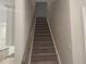 Carpeted stairway leading upstairs with light neutral walls and a wooden handrail at 1366 Lucan Ln # Wc225, Lawrenceville, GA 30043
