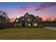 Brick front exterior of a two-story home with a large lawn at sunset at 7519 Waterview Cv, Douglasville, GA 30135
