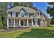 Gray two-story house with stone accents, large front porch, and landscaped yard at 6425 Riley Manor Way, Cumming, GA 30028