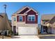 Two-story house with a maroon and beige exterior, white garage door, and landscaping at 2411 Oakleaf Cir, Lithonia, GA 30058