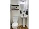 Bathroom features a white pedestal sink, a toilet, floating shelves, and modern light fixtures at 4233 Creekrun Cir, Buford, GA 30519
