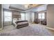 Large main bedroom with a tray ceiling, carpeting, a large bed, and two chairs by a window at 4233 Creekrun Cir, Buford, GA 30519