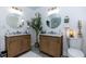 A double vanity bathroom has wood cabinets, dual round mirrors, and modern lighting fixtures at 4492 Bryten Dr, Douglasville, GA 30135