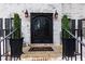 Elegant entryway featuring a black ornate double door, sconce lighting, and decorative potted plants at 4492 Bryten Dr, Douglasville, GA 30135