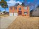 Brick two-story house with a two-car garage and a well-maintained lawn at 1043 Carriage Trace Cir, Stone Mountain, GA 30087