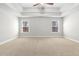 Spacious bedroom featuring neutral carpeting, two windows, ceiling fan, and tray ceiling at 2417 Kingston Heath Way, Marietta, GA 30008