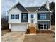 Two-story home with a two-car garage, neutral color palette, black shutters, and wooden steps leading to the front door at 478 Charleston Pl, Villa Rica, GA 30180