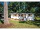 Ranch home with white brick exterior, wood accents, and a large tree in the front yard at 207 Okemah Se Trl, Marietta, GA 30060