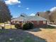 Exterior of home with a metal roof, red brick, well-manicured lawn, and patio area at 2620 Dr Bramblett Rd, Cumming, GA 30028