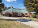 Exterior view of home showcasing a large yard, red brick, metal roof, and covered patio at 2620 Dr Bramblett Rd, Cumming, GA 30028