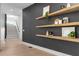 Hallway featuring hardwood floors, a dark accent wall, floating shelves, and staircase at 160 Cedarwood Ln, Roswell, GA 30075