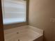 Relaxing corner bathtub with window and neutral wall colors at 606 Grenier Ter, Lawrenceville, GA 30045