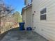 Rear exterior view with patio, trash cans, and wooded backdrop at 606 Grenier Ter, Lawrenceville, GA 30045