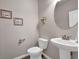 Small bathroom with pedestal sink, toilet, and round mirror at 6825 Ashford Manor Way, Cumming, GA 30040