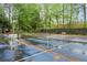View of the backyard tennis court surrounded by greenery, benches, and fencing at 3616 Longfellow Trl, Marietta, GA 30062
