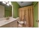 Bathroom with green walls, white vanity, and beige shower curtain at 3599 Woodbriar Cir # G, Tucker, GA 30084