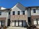 Beautiful townhome featuring a brick and painted siding exterior, complemented by a modern garage door and manicured landscaping at 214 Depot Landing Rd # 62, Auburn, GA 30011