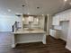 Open-concept kitchen featuring a granite island, stainless fixtures, white cabinets, and hardwood floors at 216 Depot Landing Rd # 61, Auburn, GA 30011