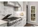 Gourmet kitchen with gas range, stainless steel hood, marble backsplash, and white cabinetry at 4152 Club Dr, Atlanta, GA 30319