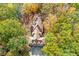 Overhead shot reveals a grand home with distinct roof architecture, privately secluded among colorful trees at 115 Russell Rd, Roswell, GA 30075
