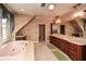 A large luxurious bathroom is complete with double sinks, a large soaking tub, and a window overlooking trees at 115 Russell Rd, Roswell, GA 30075