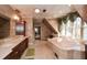 An opulent bathroom features a large soaking tub, dual sinks, elegant fixtures and a large window overlooking trees at 115 Russell Rd, Roswell, GA 30075
