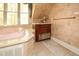 A luxurious bathroom boasts a soaking tub with gold fixtures, alongside custom cabinetry and a scenic window view at 115 Russell Rd, Roswell, GA 30075