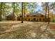 Brick home with a large front yard, set back from the road among tall trees at 115 Russell Rd, Roswell, GA 30075