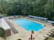Large community pool with multiple lounge chairs and covered area surrounded by lush greenery at 3091 Colonial Way # E4, Chamblee, GA 30341