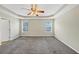 Main bedroom featuring plush carpet, neutral walls, tray ceiling, a ceiling fan, and two windows at 141 Whimsical Ct, Locust Grove, GA 30248