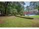 Large backyard with grassy area, stone wall, and a view of the pool at 5513 N Peachtree Rd, Dunwoody, GA 30338