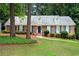 Charming brick home with blue shutters, dormers, and a well-manicured front yard with mature trees at 5513 N Peachtree Rd, Dunwoody, GA 30338