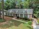 A beautiful brick home featuring blue shutters, dormer windows and mature trees around the landscaped front yard at 5513 N Peachtree Rd, Dunwoody, GA 30338