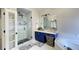 A modern bathroom with a blue vanity, glass enclosed shower, and soaking tub at 2968 Winterthur Close Nw, Kennesaw, GA 30144
