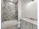 Bathroom with tub and shower featuring white vanity and gray herringbone tile at 122 Owens Mill Pl, Canton, GA 30115