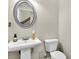 Clean powder room with pedestal sink and circular mirror at 9026 Jim Purcell Dr, Covington, GA 30014