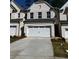 Townhome features a two-car garage and a white brick facade with black trim and a well-maintained lawn at 4150 Cavalier Way, Duluth, GA 30097