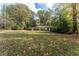 A wide shot of the well-manicured lawn and the front of the charming house surrounded by mature trees at 1141 Goodwin Ne Pl, Brookhaven, GA 30319