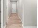 Long hallway featuring light hardwood floors, neutral walls, and a door leading to the home's entrance at 106 Cherry Glen Way, Euharlee, GA 30145