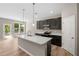 Modern kitchen features a large island, stainless steel appliances, dark cabinets, and wood floor at 106 Cherry Glen Way, Euharlee, GA 30145