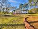 Charming single-story home with white siding, red brick foundation, and a well-maintained lawn under a clear blue sky at 555 Bridge Ave, Forest Park, GA 30297