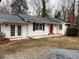 A beautifully renovated exterior features white siding, black shutters, and a striking red door for a modern, yet classic look at 240 Dogwood Dr, Canton, GA 30114
