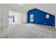 Bright carpeted room featuring a bold blue accent wall, natural light, and neutral finishes at 4450 Millenium View Ct, Snellville, GA 30039
