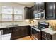 Well-lit kitchen features dark cabinets, granite countertops, and stainless steel appliances at 5016 Whiteoak Se Pointe, Smyrna, GA 30080