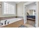 Bright bathroom with tiled tub surround, glass block window, and view to bedroom at 1004 Fairway Seven, Villa Rica, GA 30180