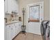 Bright laundry room featuring white cabinetry, beige tile floors and a door to the exterior at 1004 Fairway Seven, Villa Rica, GA 30180