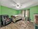 Bedroom featuring green walls, wood floors, a ceiling fan, and a comfortable recliner chair at 1349 Highway 81 E, Mcdonough, GA 30252