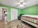 Bedroom with green walls, wood floors, white closet, recliner, and view into another room at 1349 Highway 81 E, Mcdonough, GA 30252